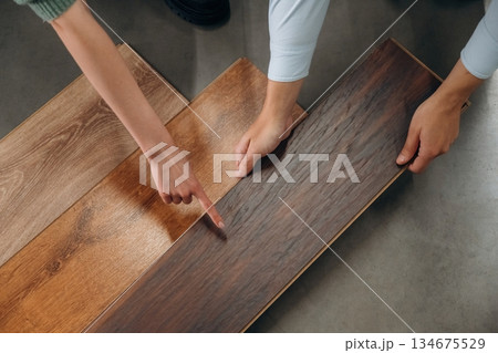 Top view, with parquet, choosing. Man and woman are in the hardware store Top view, with parquet, choosing. Man and woman are in the hardware store 134675529