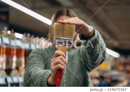 Brand new paintbrush. Close up view of woman that is in the hardware store Brand new paintbrush. Close up view of woman that is in the hardware store 134675567