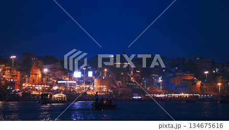 Varanasi, Uttar Pradesh, India. Evening Ganga Maha Aarti ceremony on Dashashwamedh Ghat. night time illumination lights. Cinematic Camera movement moving along riverbank embankment. View from 134675616