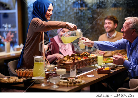 Family gathers to break fast together during Ramadan dinner in a cozy home setting with traditional food and drinks Family gathers to break fast together during Ramadan dinner in a cozy home setting with traditional food and drinks 134676258