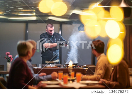 Gathering for iftar in a restaurant as a chef prepares food during Ramadan 134676275