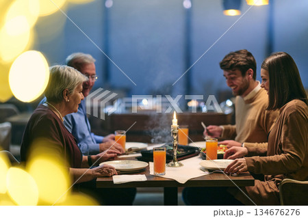 Family gathered around table for iftar meal during Ramadan at restaurant in evening with soft lighting and warm atmosphere 134676276