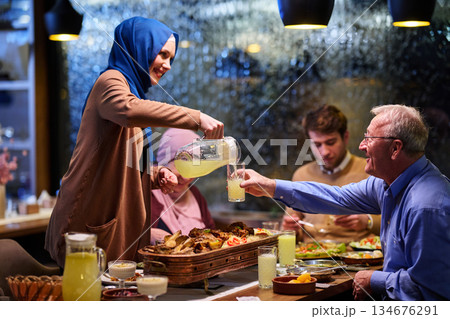 Family gathers for iftar during Ramadan with food and drinks in a warm atmosphere at a cozy restaurant setting Family gathers for iftar during Ramadan with food and drinks in a warm atmosphere at a cozy restaurant setting 134676291