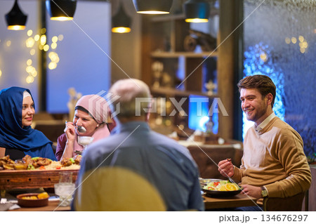 Families share iftar meals together during Ramadan in a cozy restaurant setting with warm lights and festive decor Families share iftar meals together during Ramadan in a cozy restaurant setting with warm lights and festive decor 134676297