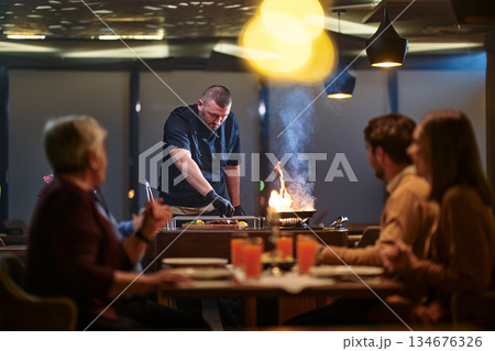 Gathering with family for iftar at a restaurant during Ramadan with a chef preparing food Gathering with family for iftar at a restaurant during Ramadan with a chef preparing food 134676326