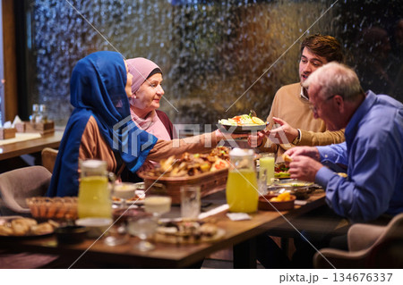 Family gathering for iftar during Ramadan with a spread of traditional dishes and drinks in a cozy restaurant setting Family gathering for iftar during Ramadan with a spread of traditional dishes and drinks in a cozy restaurant setting 134676337