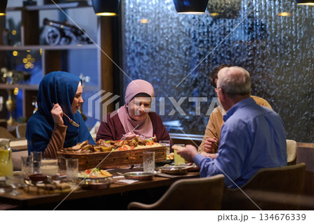 Gathering for iftar with family members sharing food and laughter during Ramadan in a warm dining environment 134676339
