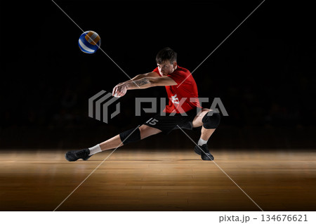 Modern mixed media shows volleyball player receiving the ball in low defensive stance. 134676621