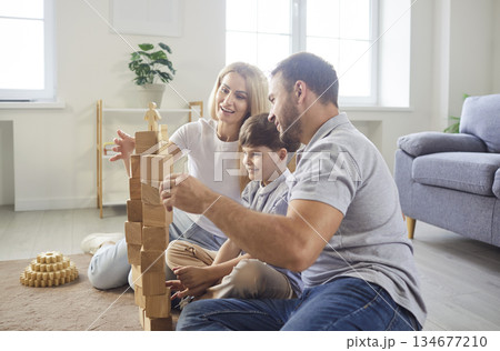 Young happy family playing kid boy building wooden pyramid in the living room at home Young happy family playing kid boy building wooden pyramid in the living room at home 134677210