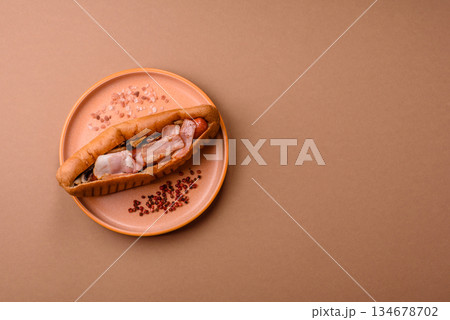 A hot dog with sausage, bacon, sauces, and a bun, unhealthy takeaway food. A hot dog with bacon 134678702
