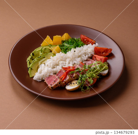 Seared tuna tataki in a bowl with sesame seeds, rice, and vegetables. Tuna tataki 134679293