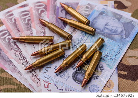 Machine gun cartridges on a camouflage background, military wallpaper. Camouflage background Machine gun cartridges on a camouflage background, military wallpaper. Camouflage background 134679928