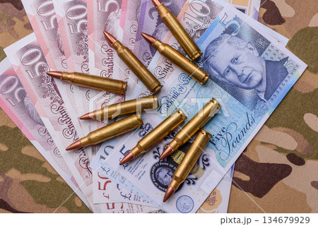 Machine gun cartridges on a camouflage background, military wallpaper. Camouflage background Machine gun cartridges on a camouflage background, military wallpaper. Camouflage background 134679929
