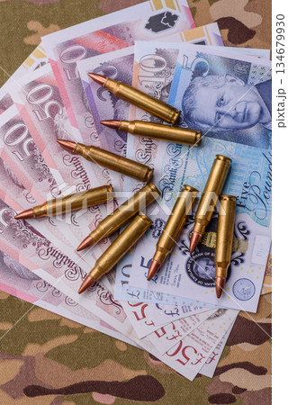 Machine gun cartridges on a camouflage background, military wallpaper. Camouflage background Machine gun cartridges on a camouflage background, military wallpaper. Camouflage background 134679930