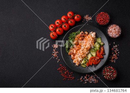 A food bowl with salmon, rice, avocado, tomatoes, and cucumbers. A salmon bowl 134681764