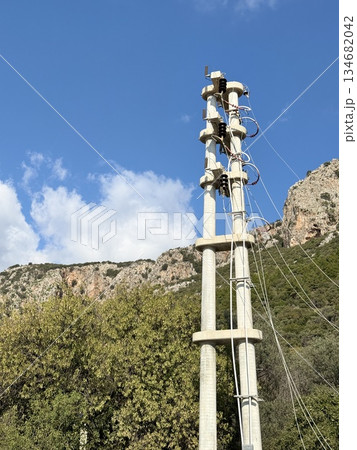 Power line against blue sky with rocky mountain background 134682042
