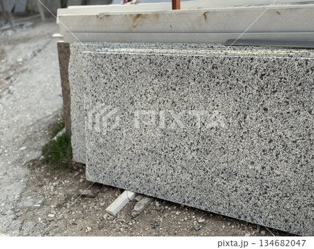 Granite slabs stacked outdoors on construction site, showcasing natural stone texture background Granite slabs stacked outdoors on construction site, showcasing natural stone texture background 134682047
