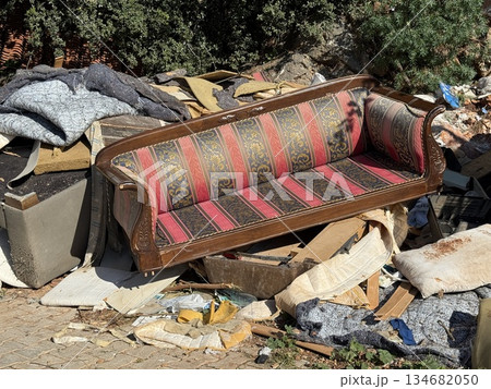 Discarded vintage sofa amidst urban waste on a sunny day, depicting environmental neglect Discarded vintage sofa amidst urban waste on a sunny day, depicting environmental neglect 134682050