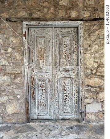 Weathered wooden door on ancient stone wall showcasing rustic textures and historical background Weathered wooden door on ancient stone wall showcasing rustic textures and historical background 134682053