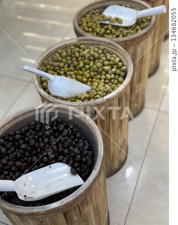 Barrels filled with assorted olives in a market setting with scoops on display Barrels filled with assorted olives in a market setting with scoops on display 134682055