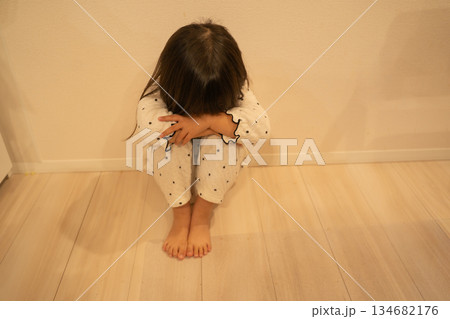 膝を抱えて顔を伏せる体育座りの子供 134682176