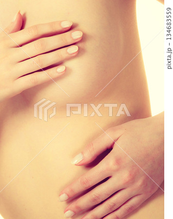 Woman examining her breasts for breast cancer Woman examining her breasts for breast cancer 134683559