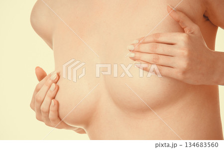 Woman examining her breasts for breast cancer Woman examining her breasts for breast cancer 134683560