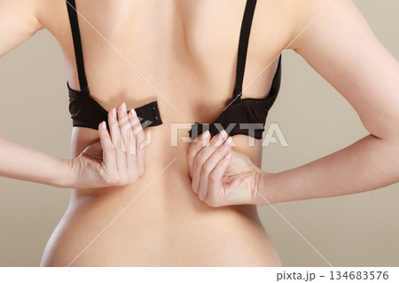Woman dressing up her bra rear view Woman dressing up her bra rear view 134683576