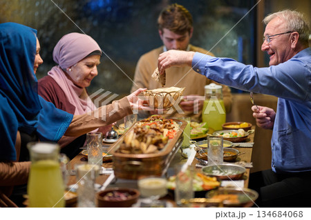 Muslim family enjoys iftar together at a restaurant during Ramadan with festive decorations and shared food Muslim family enjoys iftar together at a restaurant during Ramadan with festive decorations and shared food 134684068