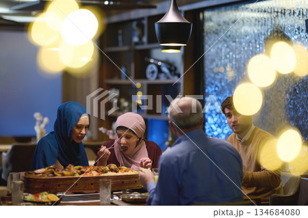 Muslim family enjoys iftar in a restaurant with Ramadan decorations and warm lighting 134684080