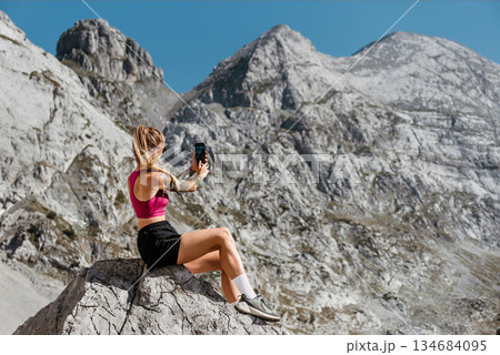 Woman Taking Pictures in Mountain Landscape 134684095