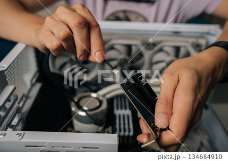 Skilled technician male hands inserting wireless network module inside computer tower, highlighting professional computer maintenance and hardware upgrade process. Concept of modern technology. Skilled technician male hands inserting wireless network module inside computer tower, highlighting professional computer maintenance and hardware upgrade process. Concept of modern technology. 134684910