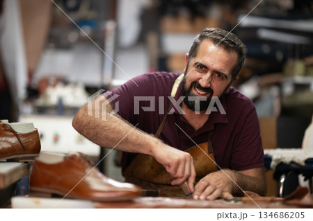 Skilled cobbler crafts leather shoes in a busy workshop, showcasing artisanal leatherwork and craftsmanship. Skilled cobbler crafts leather shoes in a busy workshop, showcasing artisanal leatherwork and craftsmanship. 134686205