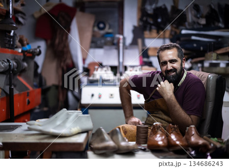 Portrait of a cobbler in his workshop, crafting leather shoes and resting relaxed 134686243