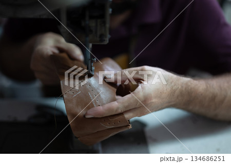 Craftsman sewing leather by hand with a sewing machine, focusing on stitching details Craftsman sewing leather by hand with a sewing machine, focusing on stitching details 134686251