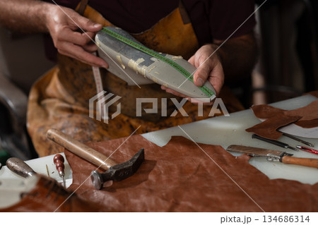 Leather artisan at work measuring leather pieces with ruler amid tools and hammered designs handmade Leather artisan at work measuring leather pieces with ruler amid tools and hammered designs handmade 134686314
