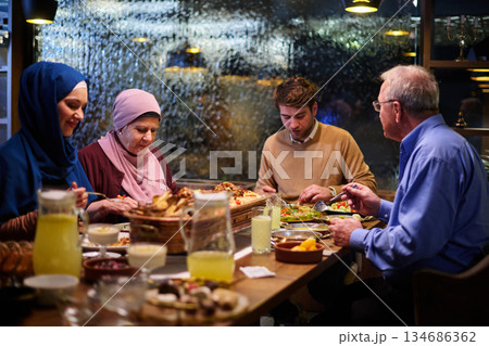 Muslim family breaks fast together in restaurant during Ramadan meal with traditional decorations and warm lighting Muslim family breaks fast together in restaurant during Ramadan meal with traditional decorations and warm lighting 134686362