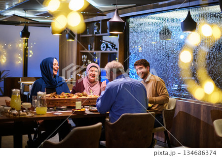 Muslim family gathering for iftar in a restaurant with Ramadan decorations and warm lighting Muslim family gathering for iftar in a restaurant with Ramadan decorations and warm lighting 134686374