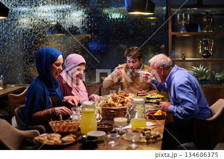 Muslim family enjoying iftar together in a restaurant during Ramadan with festive decorations and warm lighting Muslim family enjoying iftar together in a restaurant during Ramadan with festive decorations and warm lighting 134686375