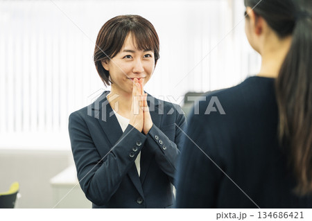 会社で同僚に仕事のお願いをする女性 134686421