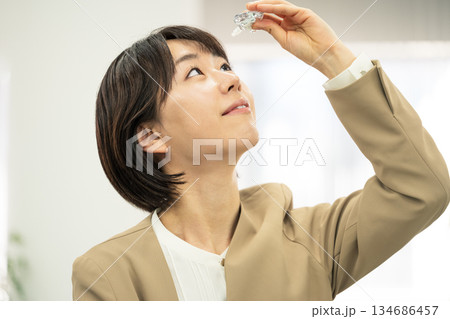 オフィスで目薬をさす若い女性 オフィスで目薬をさす若い女性 134686457