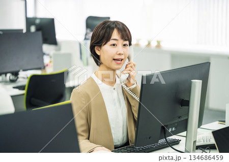 オフィスで電話応対をする若い女性 オフィスで電話応対をする若い女性 134686459