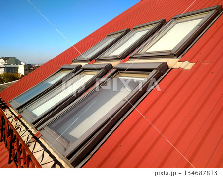 Red tiled house roof with attic windows. Roofing construction, window installation, modern architecture concept. Red tiled house roof with attic windows. Roofing construction, window installation, modern architecture concept. 134687813