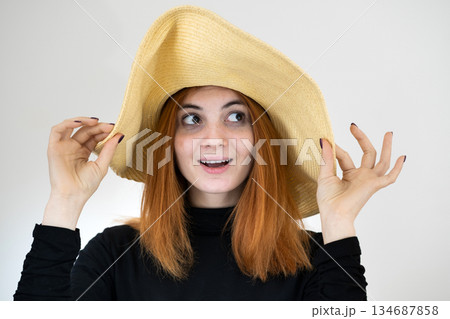 Portrait of funny redhead woman in bag yellow straw hat. Portrait of funny redhead woman in bag yellow straw hat. 134687858