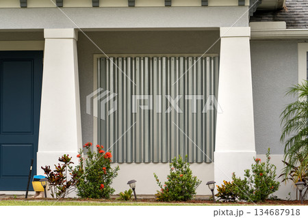 Metal storm shutters installed on residential windows in Florida as protection against hurricanes. Preventive safety measure before natural disaster Metal storm shutters installed on residential windows in Florida as protection against hurricanes. Preventive safety measure before natural disaster 134687918