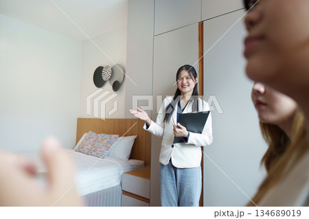 Real Estate Presentation. Agent showcasing a stylish bedroom to potential buyers. Real Estate Presentation. Agent showcasing a stylish bedroom to potential buyers. 134689019