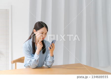 スマホを持って考える女性 スマホを持って考える女性 134689555