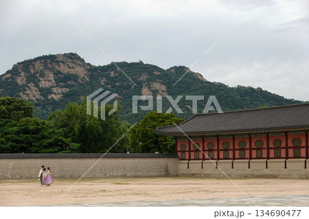 Tourists Strolling Along the Historic Stone Wall of Gyeongbokgung Palace with Ansan Mountain Towering in the Background in Seoul 134690477