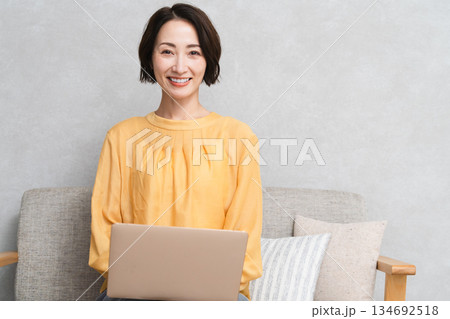ソファーに座ってノートパソコンを使う女性 ライフスタイルイメージ ソファーに座ってノートパソコンを使う女性 ライフスタイルイメージ 134692518