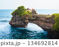Batu Bolong Temple iconic Hindu shrine on rocky arch along Bali coast attracts travelers with ocean waves, sacred Balinese architecture, Batu Bolong dramatic cliffs, spiritual atmosphere in daylight 134692814